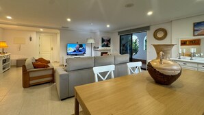 Una sala de estar moderna con un sofá gris, una mesa de comedor de madera y un jarrón grande.