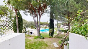 Une piscine entourée d’arbres et un bâtiment blanc.