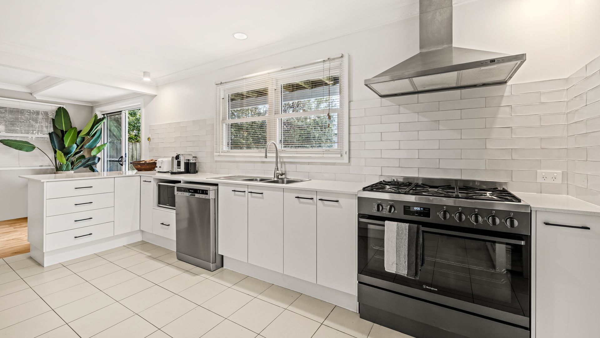 A modern kitchen with white cabinetry, a stainless steel stove, and a dishwasher.
