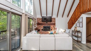 A spacious living area with a large sectional sofa, a fireplace, and a TV mounted on the wall. - Ski Slope Views, Fireplace, Game Room & Loft Retreat (Mc Gaheysville)