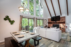 Ein modernes Wohnzimmer mit einem weißen Sofa, einem Esstisch für vier Personen und einem Kamin.