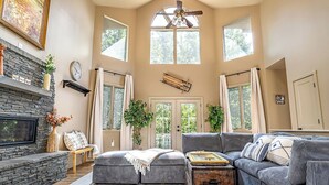 A spacious living room with a stone fireplace, a large gray sectional sofa, and a wooden coffee table. - Modern-Lux Ski Retreat-Fireplace-Hot Tub-Space! (Mc Gaheysville)