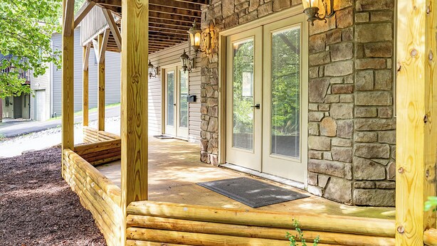 A wooden porch with stone walls and a covered area. - Modern-Lux Ski Retreat-Fireplace-Hot Tub-Space! (Mc Gaheysville)