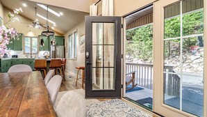 A modern kitchen with green cabinets, a wooden dining table, and a sliding glass door leading to a deck. - Modern-Lux Ski Retreat-Fireplace-Hot Tub-Space! (Mc Gaheysville)