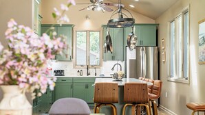 A kitchen with green cabinets, a central island with stools, and a ceiling fan. - Modern-Lux Ski Retreat-Fireplace-Hot Tub-Space! (Mc Gaheysville)
