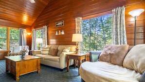 L’intérieur d’un chalet accueillant, avec un plafond en bois, un canapé, une table basse et une lampe.