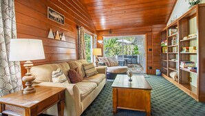Une pièce chaleureuse avec un plafond en bois, un canapé, une table basse et une bibliothèque.