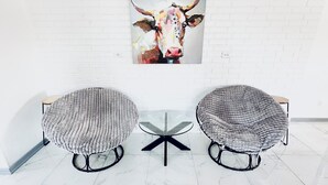 A modern room with a white brick wall, a bull painting, and two round tables with cushioned seats.