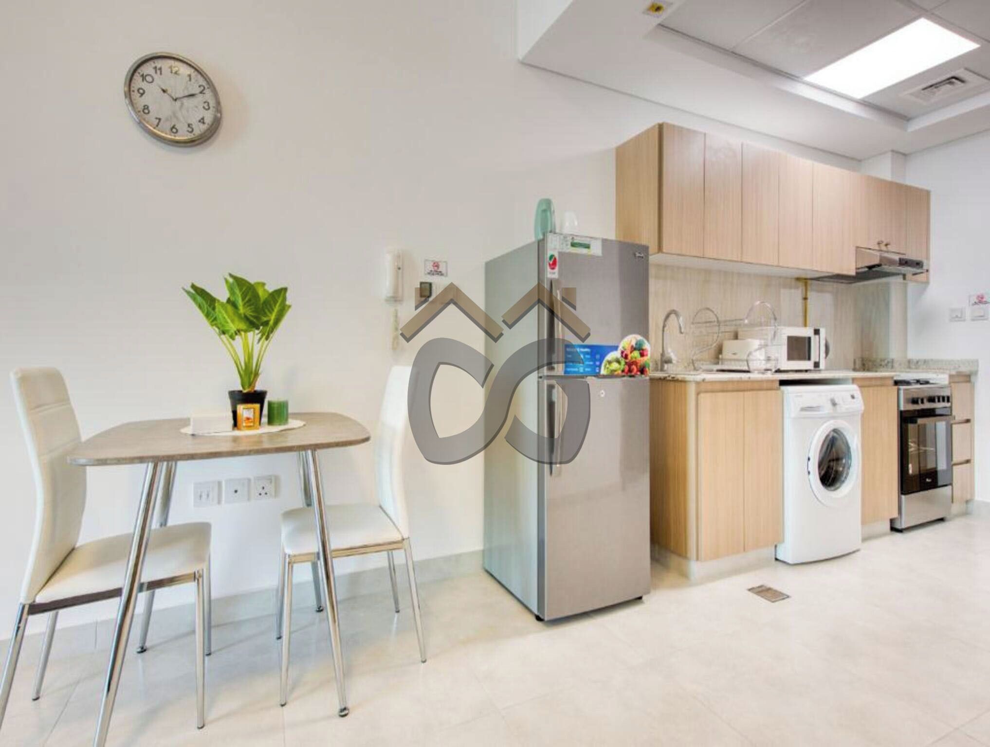 A modern kitchen with stainless steel appliances, a washing machine, and a dining area with a table and chairs.