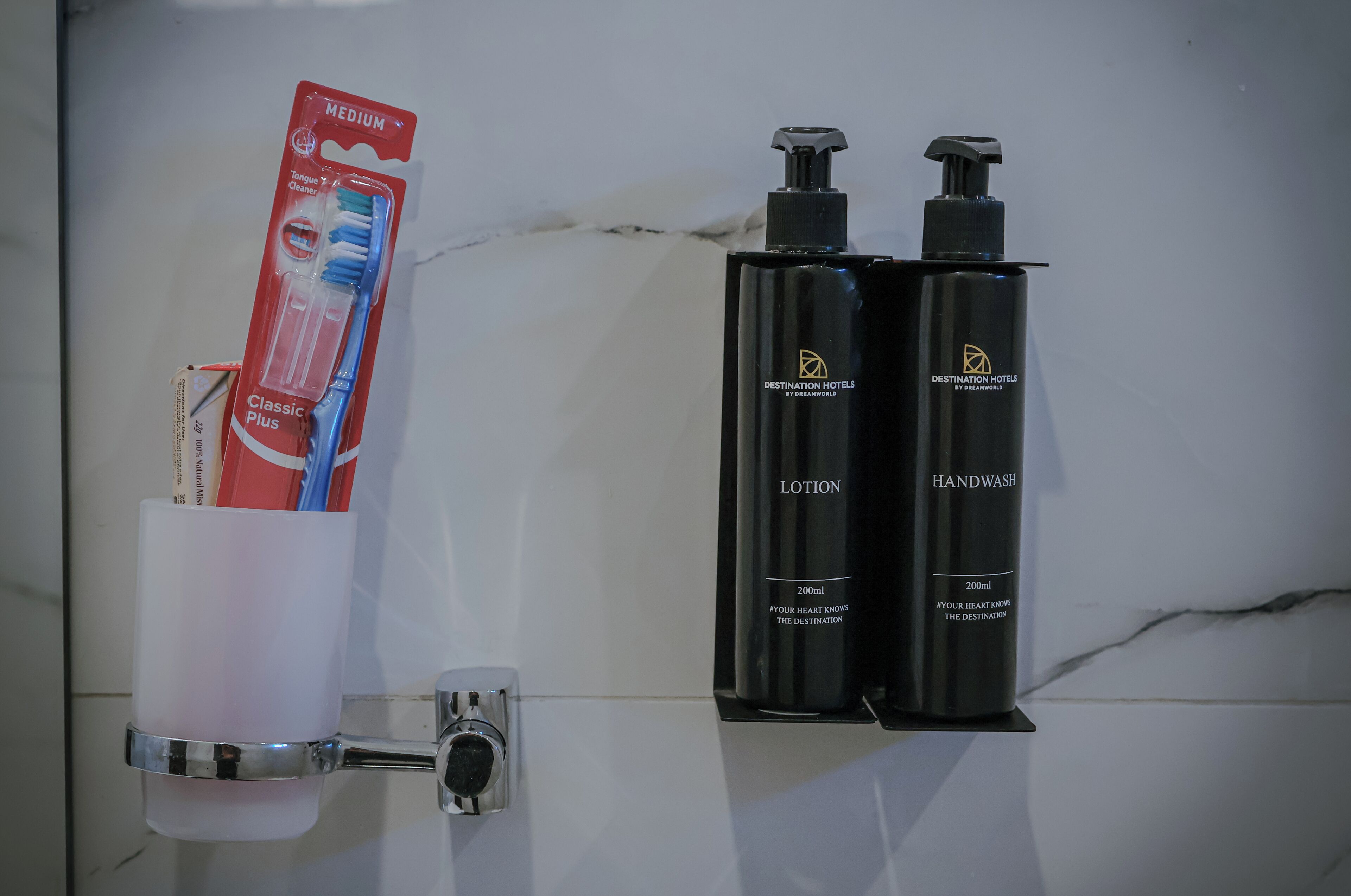 A bathroom with a handwash station, a toothbrush holder with a toothbrush, and two bottles of lotion.