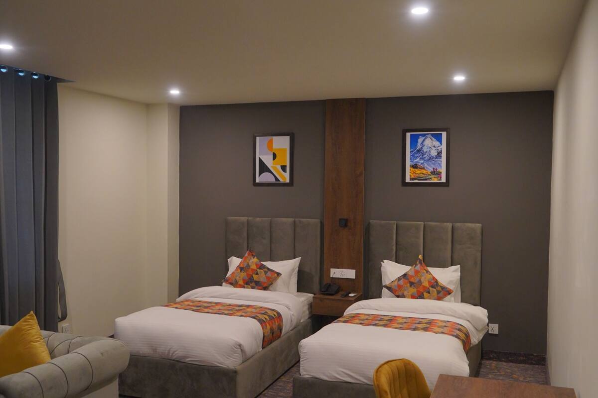 A hotel room with two beds, a sofa, a table, and a chair.