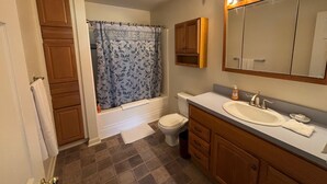Une salle de bain équipée d’une baignoire, de toilettes, d’un meuble-lavabo et d’un grand miroir.