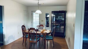 Un coin repas comprenant une table ronde, six chaises et un luminaire suspendu.
