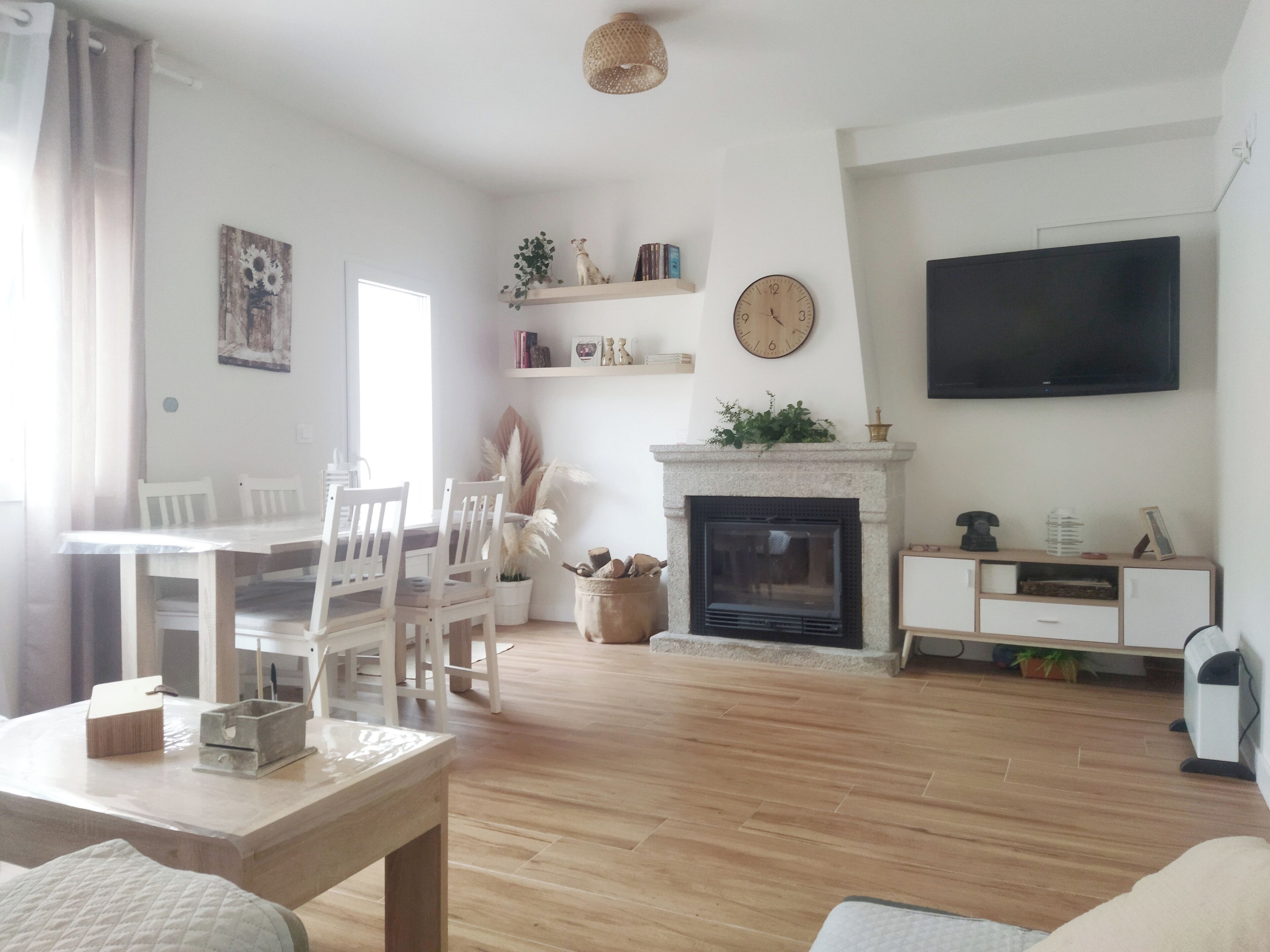 A living room with a fireplace, a television, and a dining area with chairs and a table.