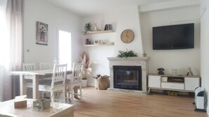 A living room with a fireplace, a television, and a dining area with chairs and a table.