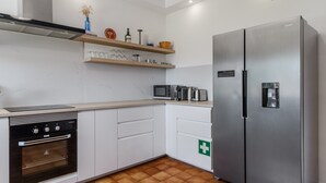 Een moderne keuken met witte kastjes, een roestvrijstalen koelkast, een inbouwoven en een magnetron.