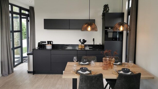 Una cocina moderna con armarios oscuros, una isla central e iluminación colgante.