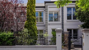 A modern building with a white facade, multiple windows, and a black metal gate. - Adelaide Oval Townhouse / Walk to the AFL & CBD (North Adelaide)