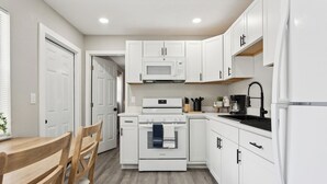 Una cocina con gabinetes blancos, un microondas, un horno y un lavamanos.
