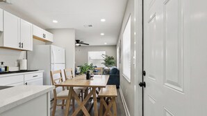 Una cocina moderna con armarios blancos, una mesa de comedor de madera y un ventilador de techo.