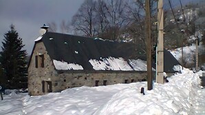 Een gebouw van steen met een sneeuwbedekte dak en schoorsteen.