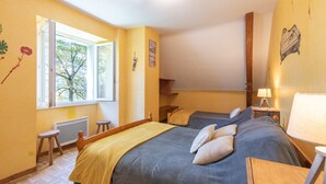 Een kamer met twee bedden, een raam, een radiator en een lamp.