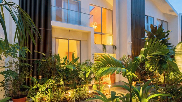 A modern house with a balcony, large windows, and a garden with various plants. - ELIVAAS Mirai Tauras 3BHK (Vagator)