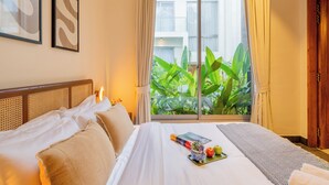 A hotel room with a bed, a window with curtains, and a view of greenery outside. - ELIVAAS Mirai Tauras 3BHK (Vagator)
