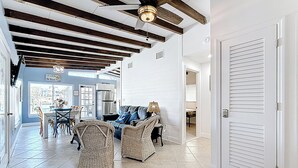 Een ruime woonkamer met een hoge plafond, een eethoek en uitzicht op buiten.