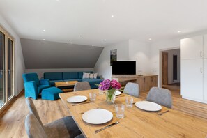 Een moderne woonkamer met een eettafel voor vier personen, een bank en een televisie.