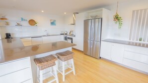 A modern kitchen with a large island, white cabinetry, and a stainless steel refrigerator.