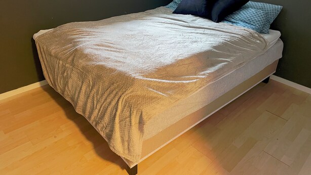 Un lit avec une couverture à motifs, des oreillers et un plancher en bois.