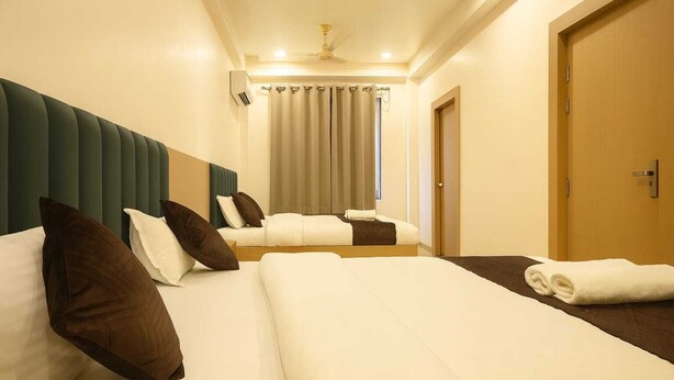 A hotel room with two beds, a wooden door, and a curtain. - Hari Niwaas Guest House by VM Stays (Varanasi)