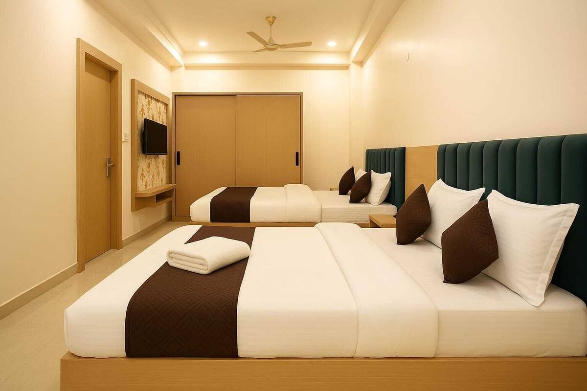 A hotel room with two beds, a TV, a ceiling fan, and a wardrobe.