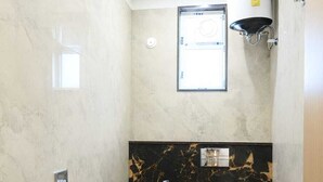 A bathroom with a marble vanity, a toilet, a shower, and a water heater. - Hari Niwaas Guest House by VM Stays (Varanasi)