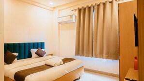 A hotel room with a bed, a TV, a wardrobe, and a window with curtains. - Hari Niwaas Guest House by VM Stays (Varanasi)