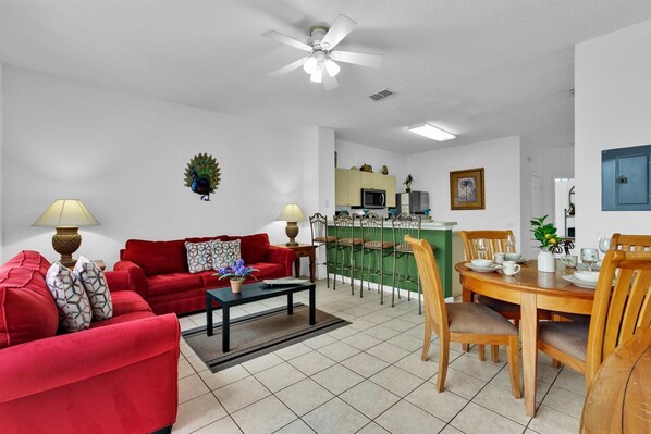 A living room with a red sofa, a coffee table, and a dining area with a wooden table and chairs. - SPD2319 Summary:<br>Our (Kissimmee)