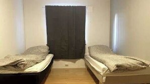 A small, narrow room with two single beds, a wooden floor, and a dark door at the far end. - 3-bedroom apartment with free parking in central Tromsø (Troms)