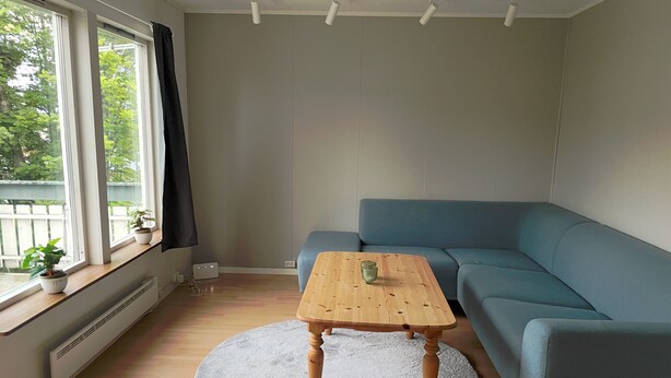 A living room with a blue sofa, a wooden coffee table, and a round rug. - 3-bedroom apartment with free parking in central Tromsø (Troms)
