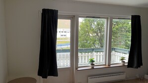 A room with a large window, a radiator, a small table, and a potted plant on the windowsill. - 3-bedroom apartment with free parking in central Tromsø (Troms)