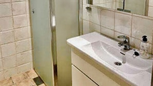 A bathroom with a glass shower enclosure, a sink with a mirror, and tiled walls. - 3-bedroom apartment with free parking in central Tromsø (Troms)
