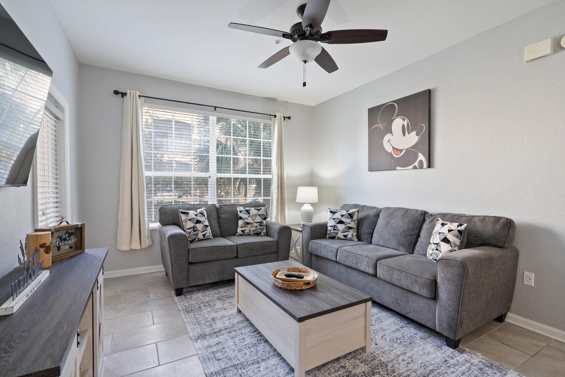 Ein modernes Wohnzimmer mit zwei grauen Sofas, einem Couchtisch und einem Deckenventilator.