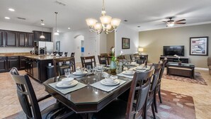 A modern kitchen with dark cabinets, a granite countertop, and a dining area with a glass table set for six. - Cup8931 (Kissimmee)