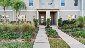 A modern two-story house with a central entrance, a driveway, and a well-maintained garden.