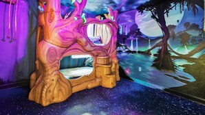 Een kamer met een uniek bed in de vorm van een boom, een sterrenhemel en een muurschildering van een nachtlandschap met watervallen.