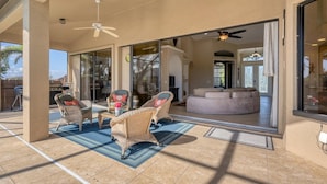 A covered patio area with wicker furniture, a glass door leading to an interior space, and a ceiling fan. - OBS119 Summary:<br>Cape (Cape Coral)