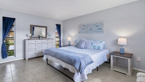 A bedroom with a bed, bedside tables, a dresser, a mirror, and a window with curtains. - Cod917 (Punta Gorda)