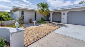 A modern house with a garage, a palm tree, and a well-maintained garden with pebbles and plants. - Cod917 (Punta Gorda)
