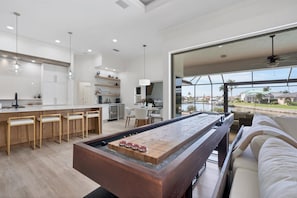 A modern kitchen with a bar area, dining space, and a view of the water.