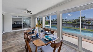 A dining area with a view of a swimming pool and a residential neighborhood.